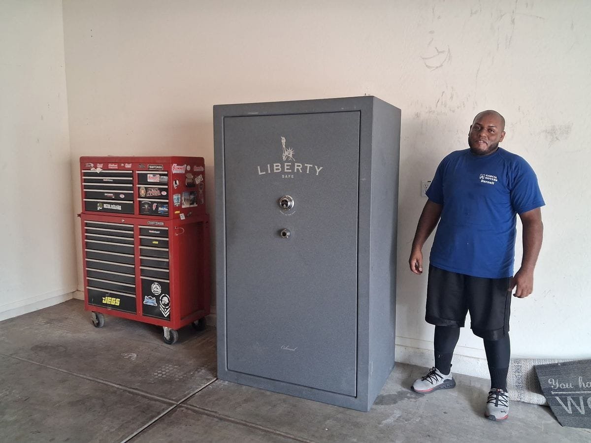 A Garcia mover standing beside a large gun safe in a garage