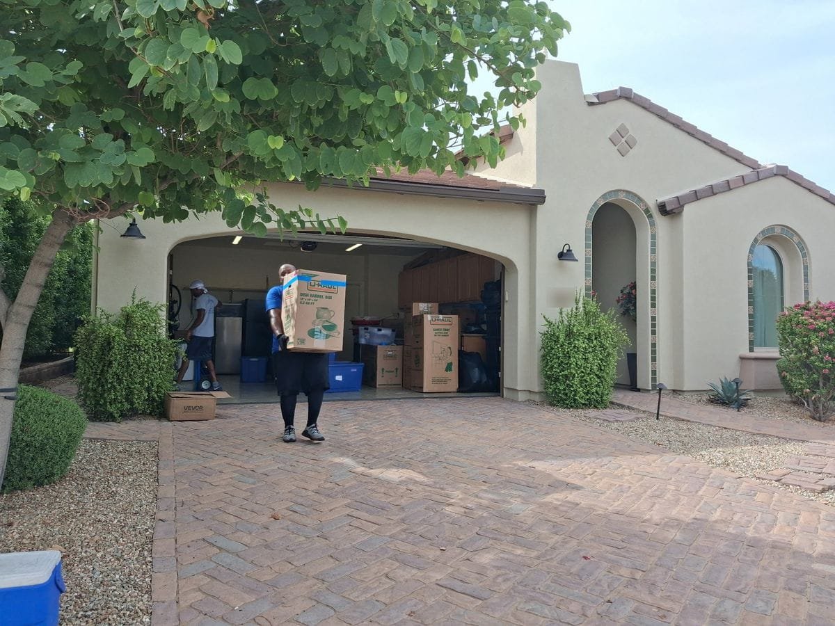 Garcia movers carrying boxes through the garage of a stucco home
