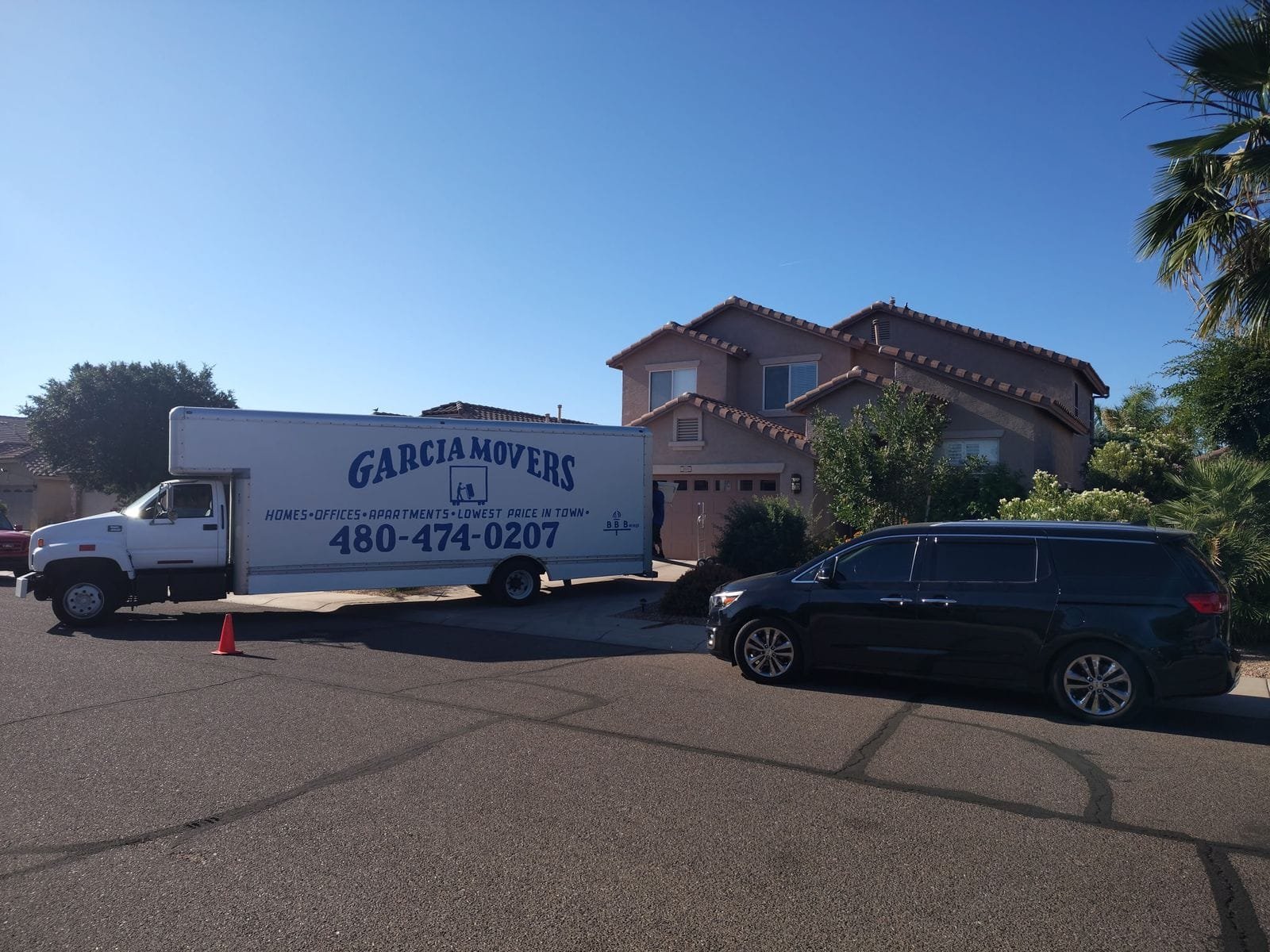 A Garcia Movers truck parked at a two-story stucco home