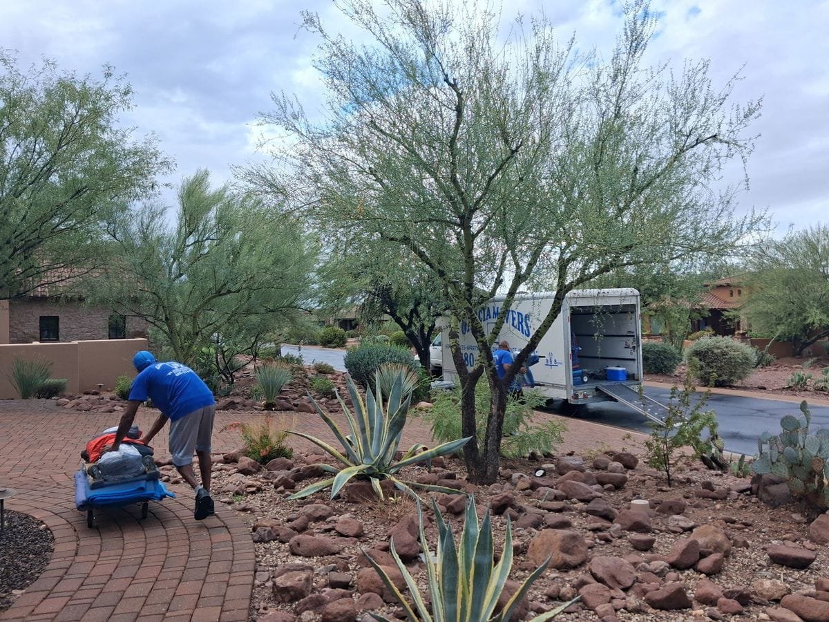 A Garcia mover rolling a loaded cart along a paver walkway through desert landscaping