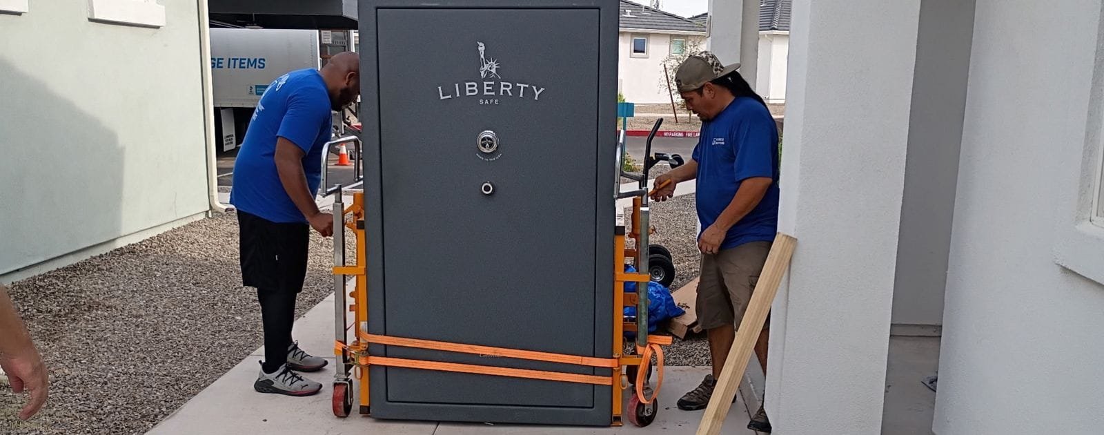 Two Garcia movers strapping a large gun safe onto a heavy-duty dolly